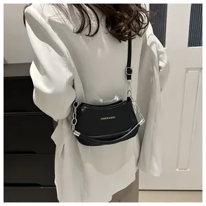 Gros plan d'un sac bandoulière en cuir noir avec chaîne argentée et texte doré