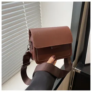 Detail of vintage brown square bag with matte faux leather and wide woven shoulder strap