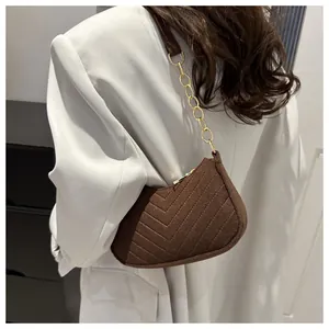 Detailed shot of brown crescent bag with herringbone stitching and gold chain strap