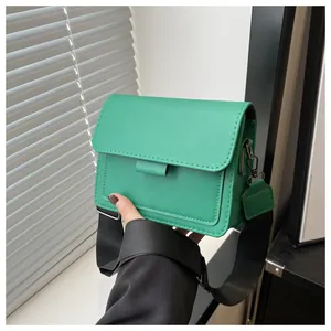 Detail of green minimalist crossbody bag with wide nylon strap and leather tag
