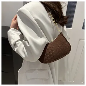 Brown half-moon crossbody bag with V-quilted texture and gold chain strap on model