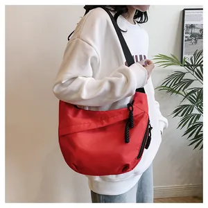 Detailed view of red nylon crescent bag with adjustable black strap and woven zipper pull