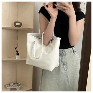 Detail of off-white leather tote bag with metal rivet hardware and minimalist design