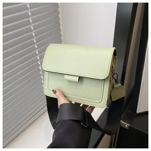 Detail of light green leather crossbody bag with wide strap and flap closure