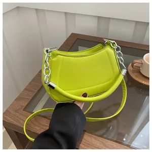 Détail du sac à main vert fluo en similicuir avec chaîne argentée et lettrage embossé