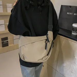 Minimalist khaki crescent messenger bag with adjustable strap worn by a model