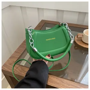 Détail du sac croissant vert vif avec poignée en chaîne métal et bandoulière