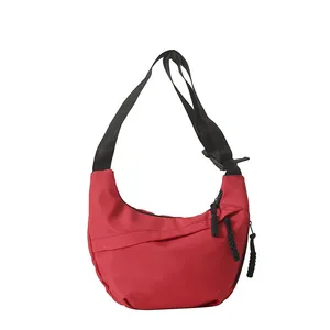 Red nylon crescent tote bag with black zipper detail and adjustable shoulder strap