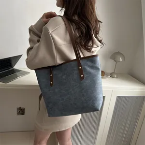 Minimalist large-capacity tote bag in blue-grey with brown leather straps and metal rivets