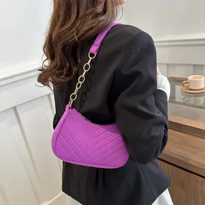 Chic purple quilted crossbody bag with gold chain strap worn by a model in lifestyle setting
