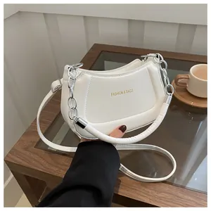 Détail d'un sac demi-lune blanc avec texte doré et décoration de chaîne argentée