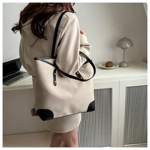 Detalle del bolso tote minimalista con ribete negro y remaches de metal dorado