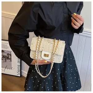 Detail of woven straw saddle bag featuring floral embroidery and golden metal twist lock