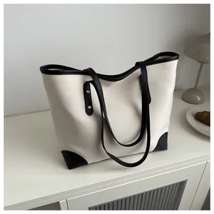 Detalle de bolso tote de lona con adornos de cuero negro y remaches metálicos
