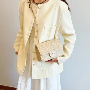 Women's woven straw saddle bag with floral embroidery and gold chain strap in beige