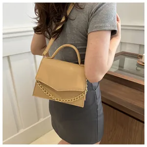 Side view of khaki leather crossbody bag with gold chain and V-shaped flap on a model