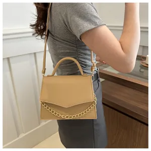Close-up of khaki shoulder bag with gold chain decoration and crocodile embossed texture