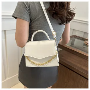 Detail view of white crossbody bag featuring gold chain and animal leather texture