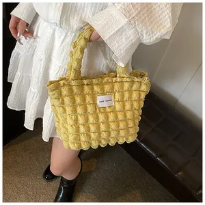 Macro detail of yellow bubble texture tote bag with Love Fashion tag on white dress