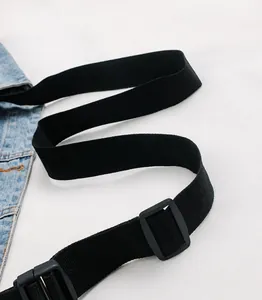 Detail of adjustable black nylon strap with plastic buckle on a blue denim waist bag