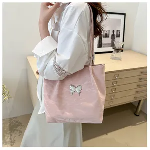 Détail du cabas rose clair avec emblème papillon argenté et texture satinée plissée