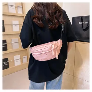 Close-up of pink nylon waist bag with floral embroidery and adjustable strap on a model