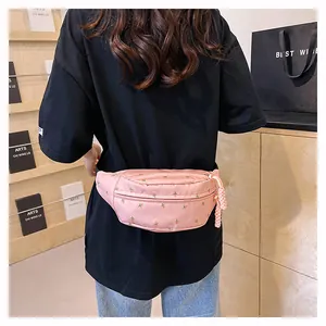 Detailed back view of a light pink waist bag with floral embroidery on a model