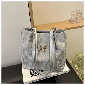 Détail du sac cabas plissé argenté avec finition métallique et ornement papillon en métal