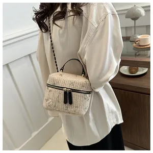 Detailed view of woven straw box bag with floral embroidery and chain shoulder strap