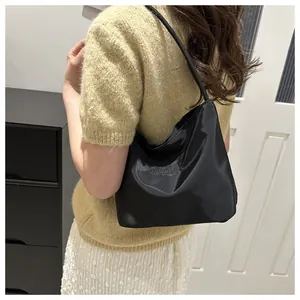 Detail of black hobo shoulder bag with and upwards embroidery shown on model