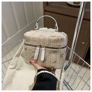 Detail of straw woven crossbody bag with green floral embroidery and metal chain strap