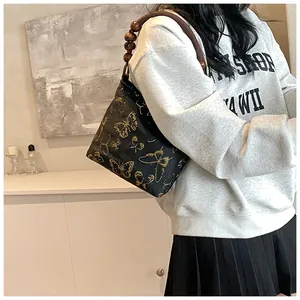 Borsa a spalla nera con ricamo a farfalla dorata e tracolla in perle di legno
