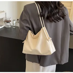 Close-up of a cream-colored soft leather tote bag with knotted drawstring details