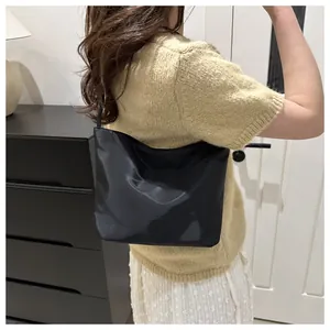 Close-up of black glossy shoulder bag featuring embossed always and upwards text