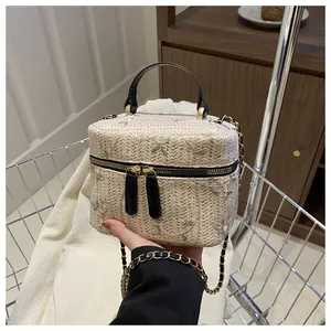 Detailed close-up of straw woven box bag with green leaf embroidery and gold zipper