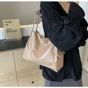 Detailed side view of beige soft leather tote bag worn by a model in a minimalist style