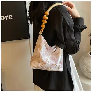 Dettaglio ricamo farfalla su borsa in raso con manici in perline di legno vintage