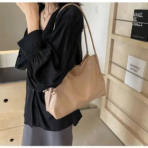 Side view of beige soft leather tote bag worn by model for minimalist daily commuting