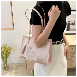 Close-up of pink tote bag featuring delicate peony embroidery and tassel detail