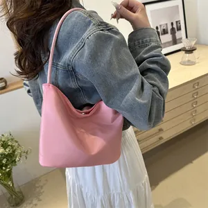 Pink minimalist bucket bag with onwards and upwards embossed text shown on a model shoulder