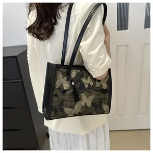 Detail of vintage black tote bag with gold butterfly embroidery and long tassel charm