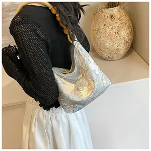 Dettaglio borsa a spalla jacquard floreale celeste con manico di perle color ambra