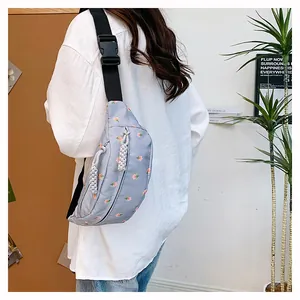 Detail of light blue crossbody waist bag with pink tulip pattern and adjustable strap