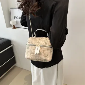 Minimalist beige woven straw bucket bag with green floral embroidery and gold chain strap