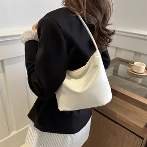 Minimalist white hobo bag with embossed text pattern worn over the shoulder by a model