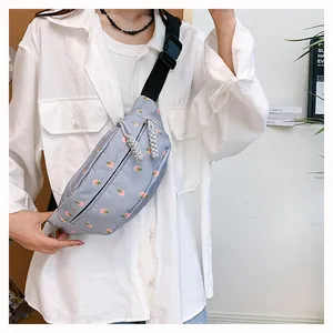 Close-up of light blue floral waist bag with double zippers and woven rope pullers