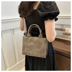 Detail van retro bruine lederen handtas met contraststiksels en geweven schouderband