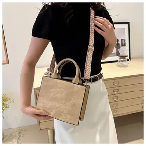Detail van beige vierkante tas met brede stoffen schouderriem in lifestyle-scène