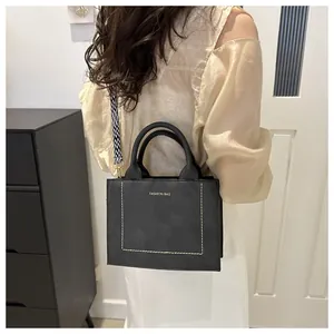 Detail van zwarte crossbodytas met geweven brede riem en modieus logo-opdruk