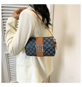 Dettaglio della borsa a spalla monogram vintage con finiture in pelle su modella in blazer